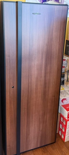 Transtherm Utility wine cabinet in tobacco wood finish standing beside stacked moving boxes